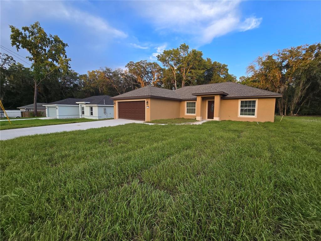 A single-story tan house with a brown garage door and a grassy front yard — 203 EMERALD ROAD, OCALA, FL