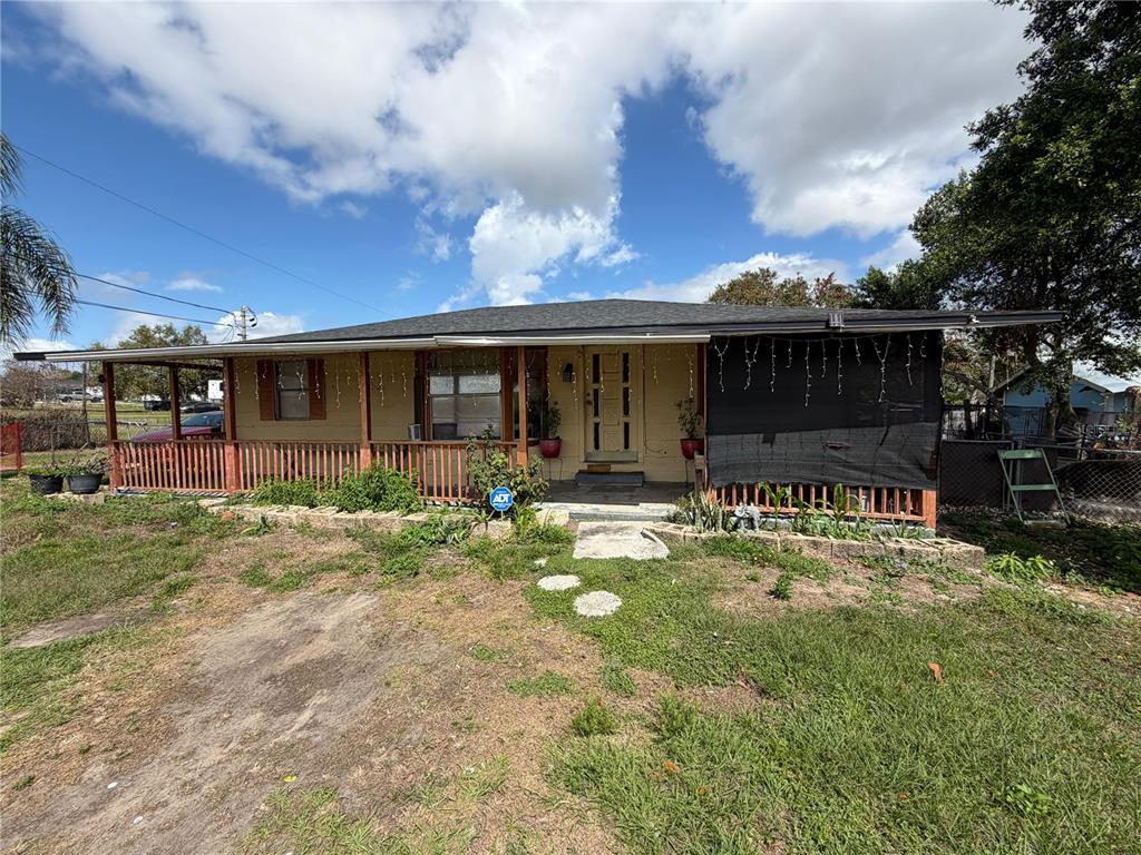 A single-story house with a covered front porch, wooden railing, and a dark shingled roof — 2300 SMITH ROAD, HAINES CITY, FL