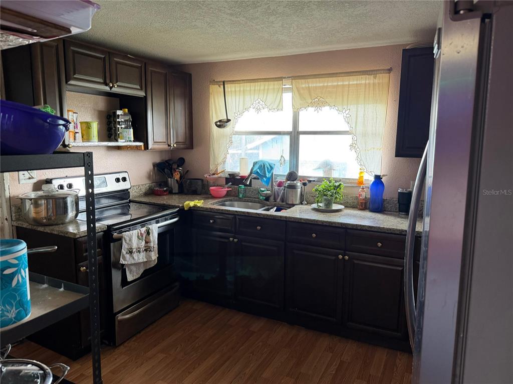 A kitchen features dark wood cabinets, granite countertops, stainless steel appliances, and a window — 2300 SMITH ROAD, HAINES CITY, FL