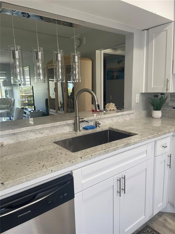 A kitchen features white cabinets, granite countertops, a stainless steel sink, and pendant lighting — 5724 LA PUERTA DEL SOL BOULEVARD UNIT 248, ST PETERSBURG, FL