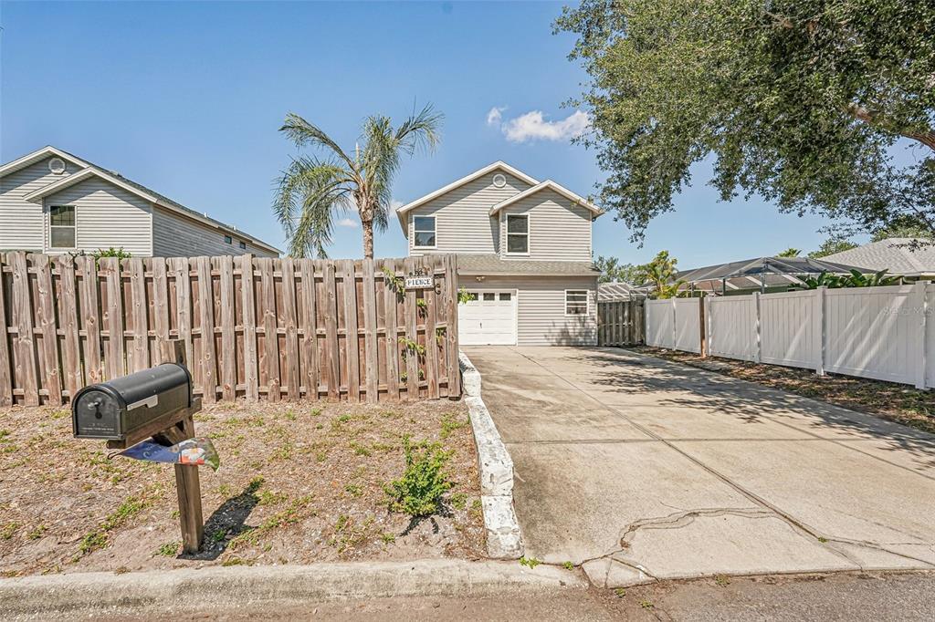 A two-story house with light gray siding, a white garage door, and a concrete driveway — 5102 MOELLER AVENUE, SARASOTA, FL