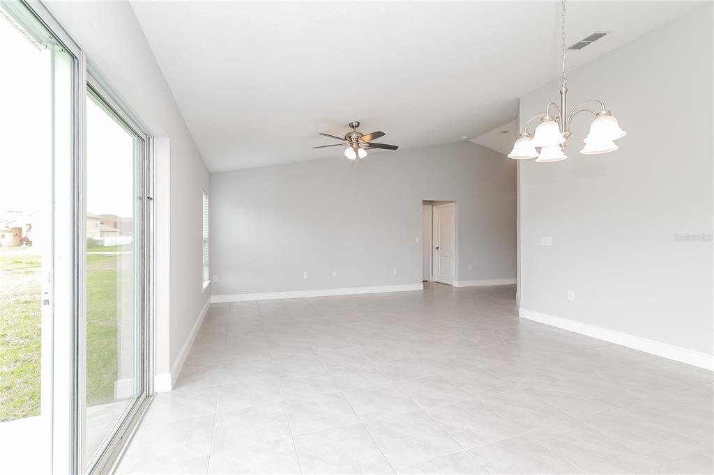 A bright, open-concept living area features light gray walls, tile flooring, and a ceiling fan — 280 BECKENHAM DRIVE, KISSIMMEE, FL