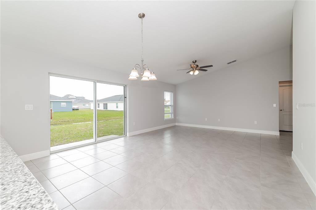 A bright, open-concept living area features light gray walls, tile flooring, and a sliding glass door — 280 BECKENHAM DRIVE, KISSIMMEE, FL
