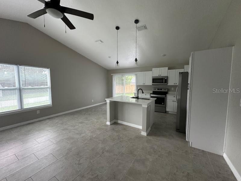 A kitchen with a central island and stainless steel appliances opens into a living area — 1809 IROQUOIS DRIVE, APOPKA, FL