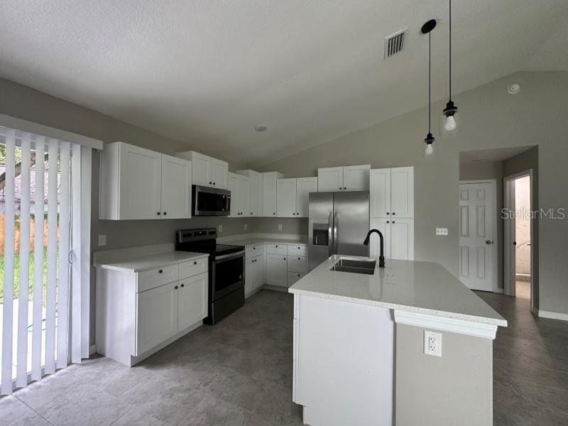 A modern kitchen features white cabinets, stainless steel appliances, a center island, and tile flooring — 1809 IROQUOIS DRIVE, APOPKA, FL