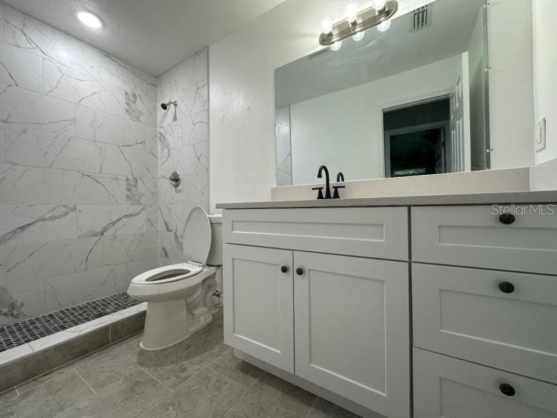 A bathroom with a white vanity, a toilet, and a walk-in shower with marble-look tiles — 1809 IROQUOIS DRIVE, APOPKA, FL