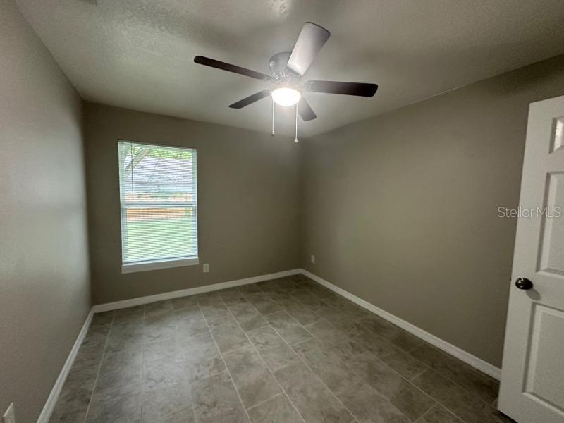 A bedroom with gray walls, tile flooring, a ceiling fan, and a single window — 1809 IROQUOIS DRIVE, APOPKA, FL