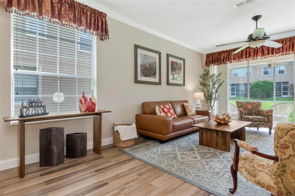 A living room features a leather sofa, patterned armchairs, a wooden coffee table, and wood-look flooring — 4111 BISMARCK PALM DRIVE, TAMPA, FL