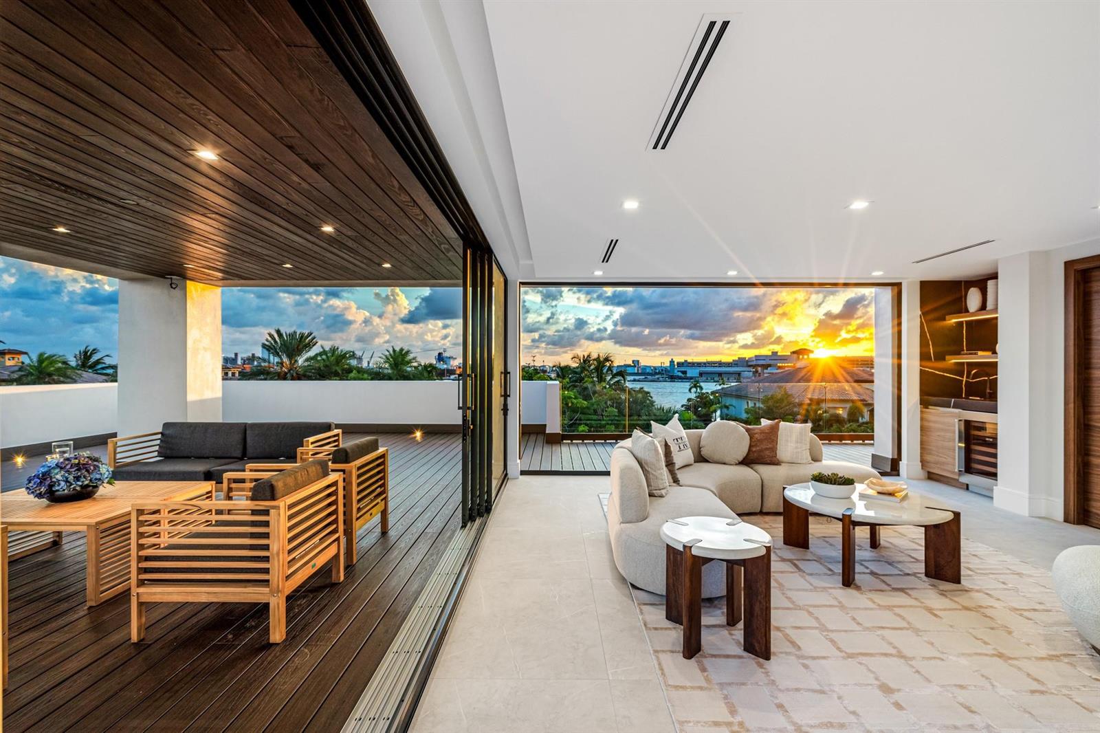 A modern living room opens to a spacious outdoor deck with sunset water views — 2000 Harbourview Drive, Fort Lauderdale FL 33316, FORT LAUDERDALE, FL
