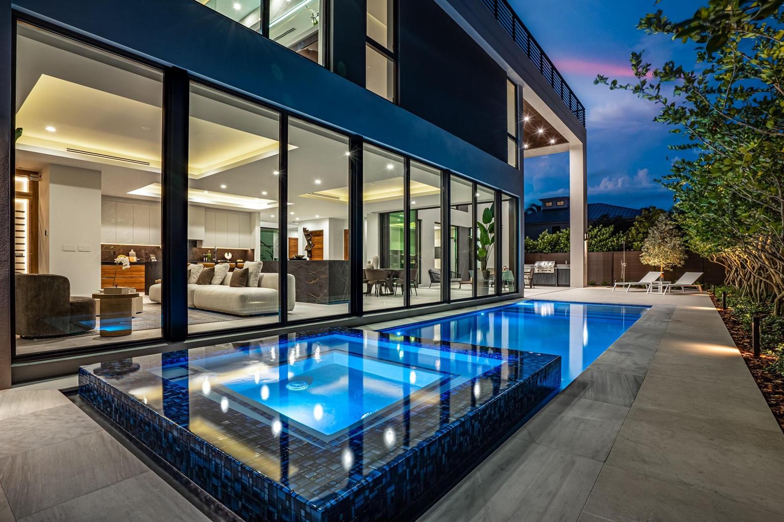 A modern two-story house with floor-to-ceiling windows overlooks a glowing blue swimming pool and spa — 2000 Harbourview Drive, Fort Lauderdale FL 33316, FORT LAUDERDALE, FL
