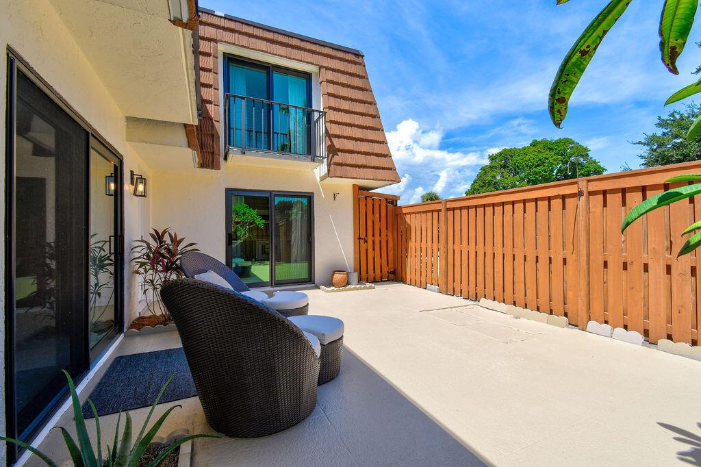 A patio with a wicker chair, sliding glass doors, and a wooden privacy fence — 3900 SE County Line Road # 22a, Jupiter FL 33469, JUPITER, FL