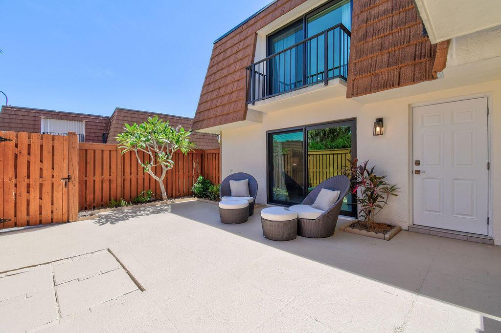A patio features two wicker chairs with ottomans, a small tree, and a white door — 3900 SE County Line Road # 22a, Jupiter FL 33469, JUPITER, FL