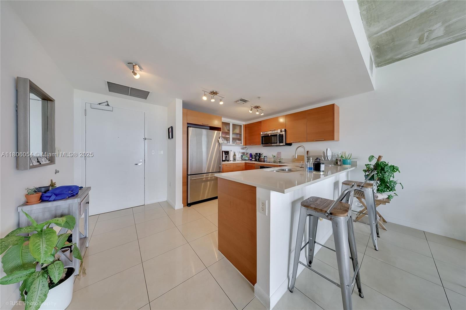 A kitchen features light wood cabinets, stainless steel appliances, a white countertop, and bar stools — 3250 NE 1st Ave # 1007, Miami FL 33137, MIAMI, FL