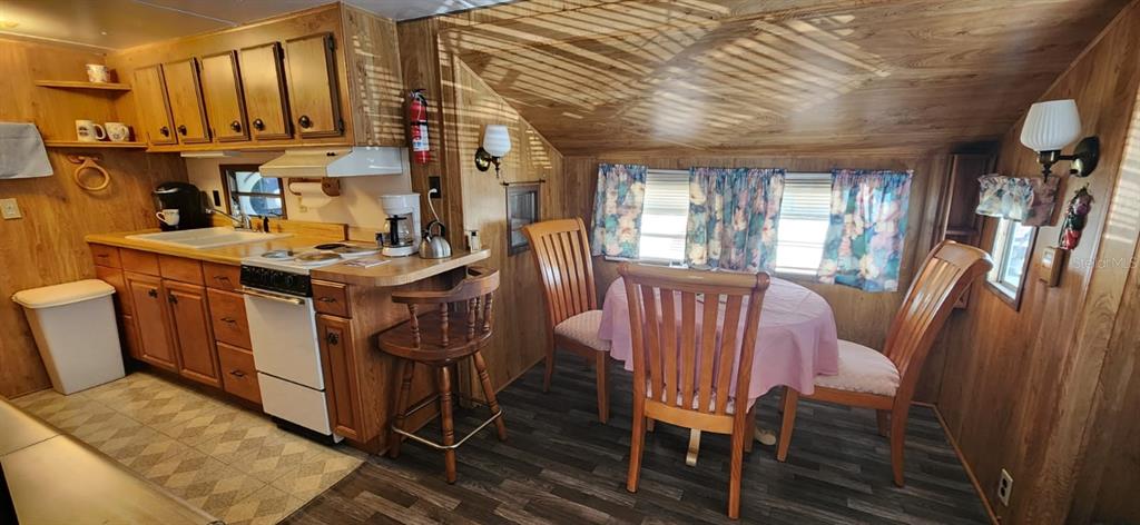 A kitchen and dining area with wood-paneled walls, wooden cabinets, and a small round table — 138 FLAMINGO STREET, DAVENPORT, FL