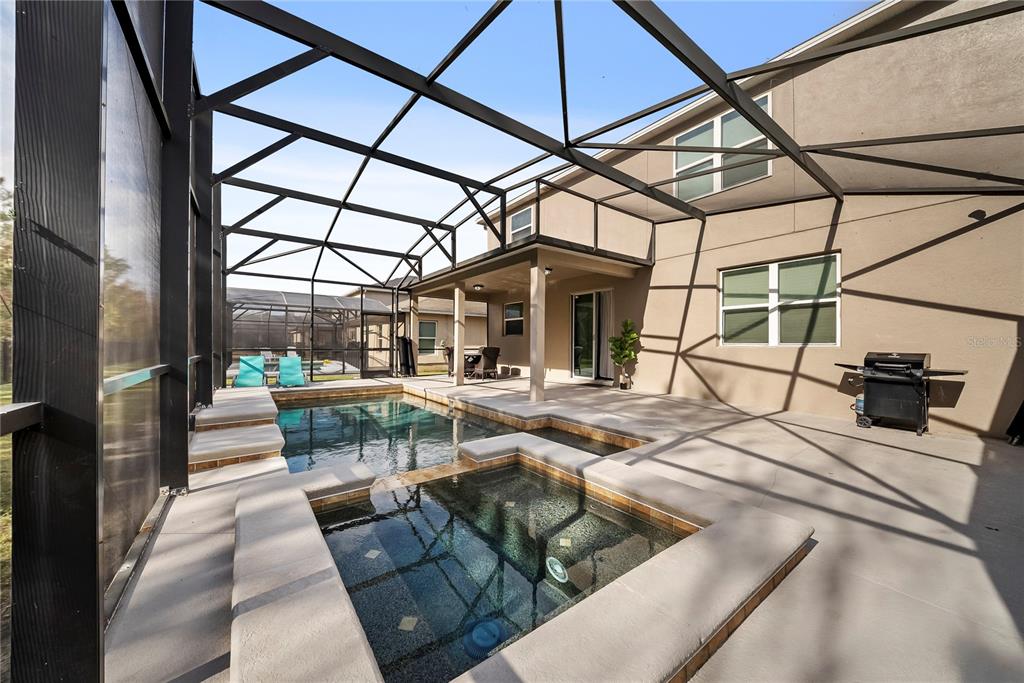 A screened-in patio features a swimming pool, a spa, and a grill on the deck — 4736 BLUE DIAMOND STREET, KISSIMMEE, FL
