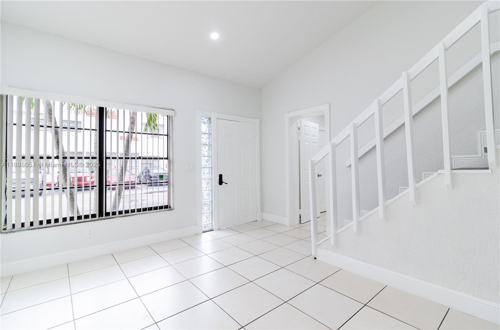 An entryway features white tile flooring, a staircase with a white railing, and a window — 217 NW 109th Ave # 217, Miami FL 33172, MIAMI, FL
