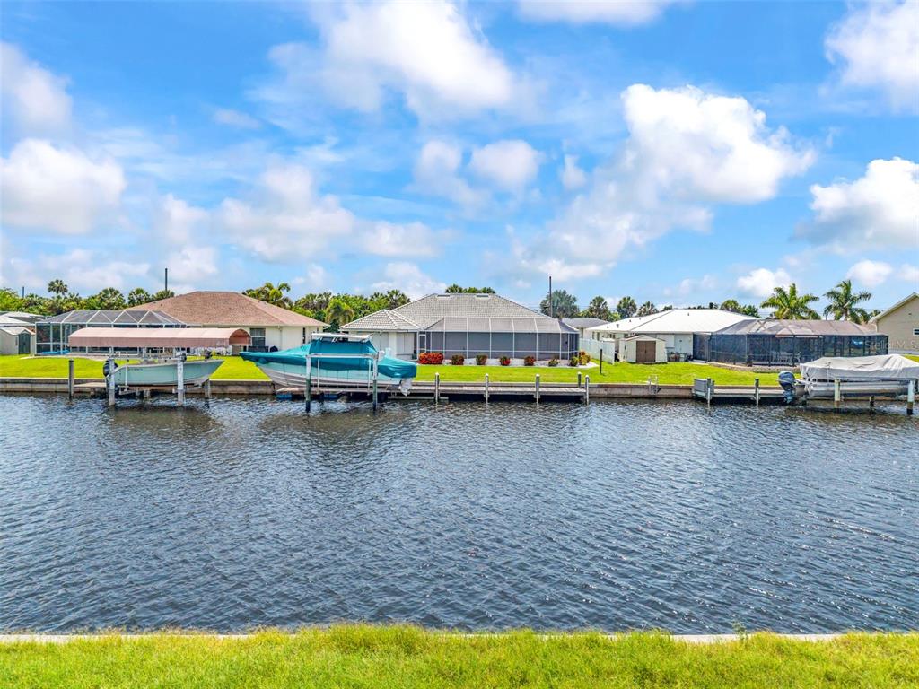A canal view of several houses with boat lifts and docks under a cloudy sky — 4366 WYNKOOP CIRCLE, PORT CHARLOTTE, FL