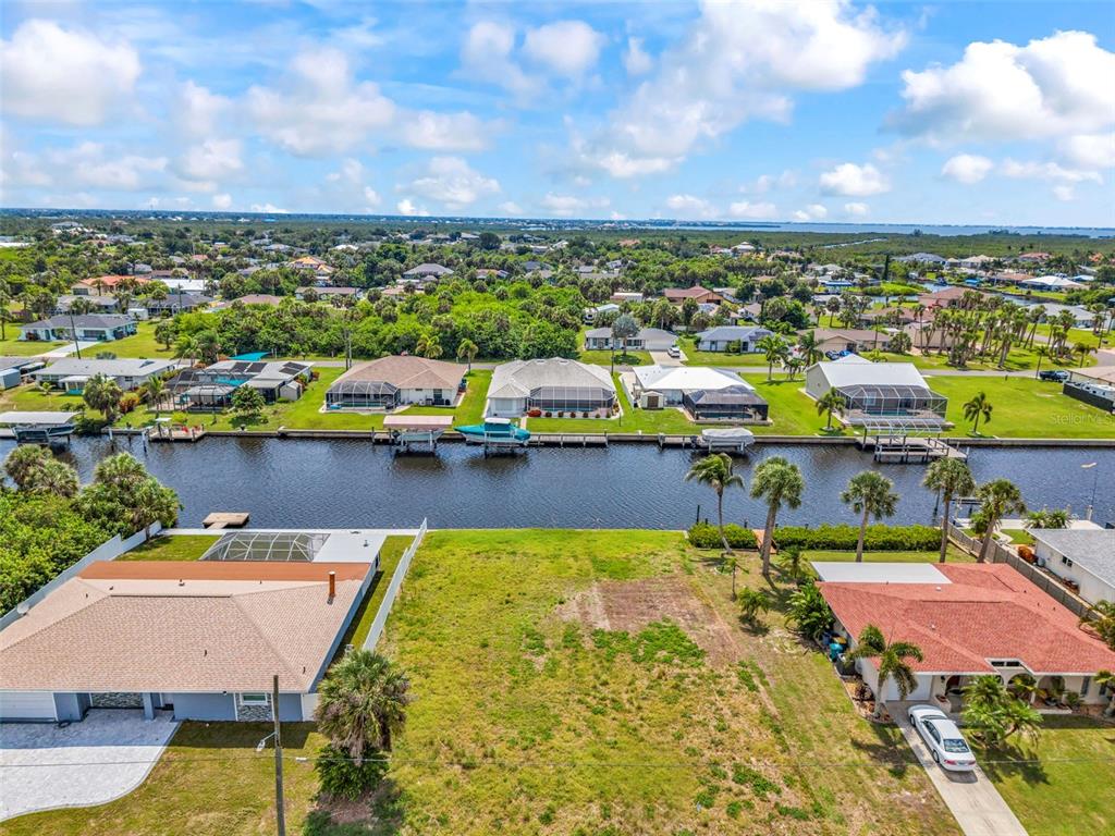 An aerial view shows a vacant waterfront lot situated between two residential homes — 4366 WYNKOOP CIRCLE, PORT CHARLOTTE, FL