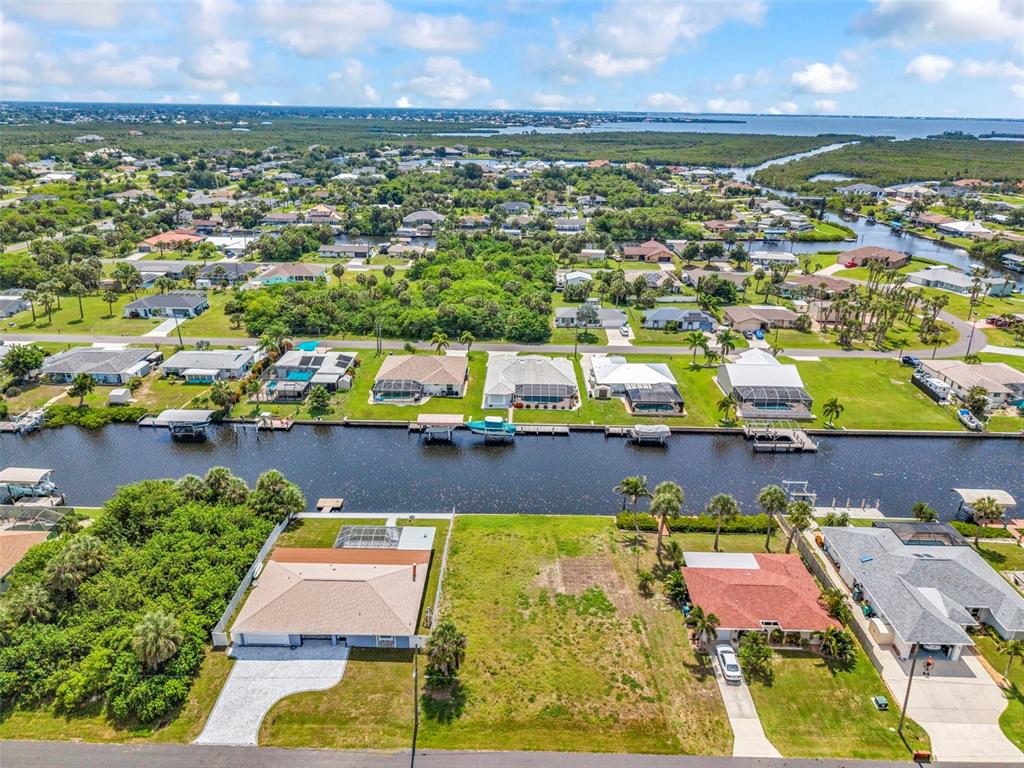 An aerial view shows a vacant waterfront lot situated between two residential houses — 4366 WYNKOOP CIRCLE, PORT CHARLOTTE, FL