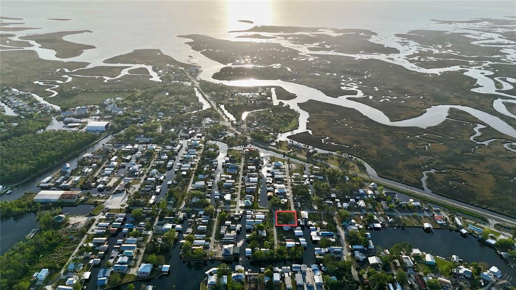 An aerial view shows a coastal neighborhood with a red-outlined lot near a waterway — 249 SE 228 STREET, SUWANNEE, FL