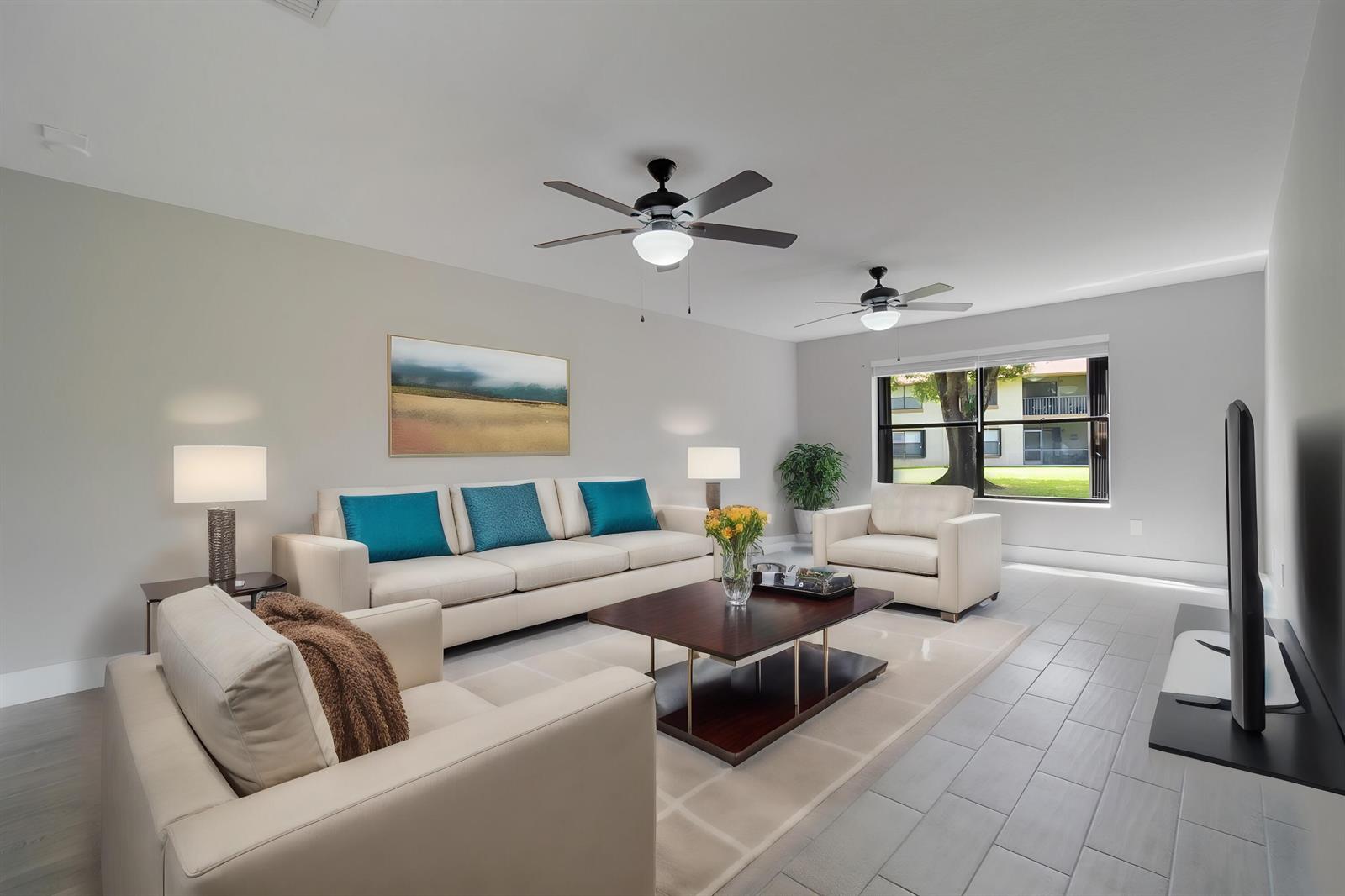 A living room features light-colored tile floors, a beige sofa, two armchairs, and ceiling fans — WELLINGTON, FL