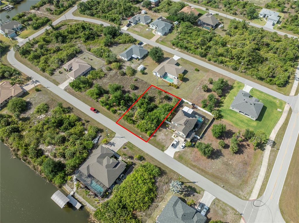 An aerial view shows a vacant, rectangular residential lot outlined in red within a neighborhood — 14337 EDNA CIRCLE, PORT CHARLOTTE, FL