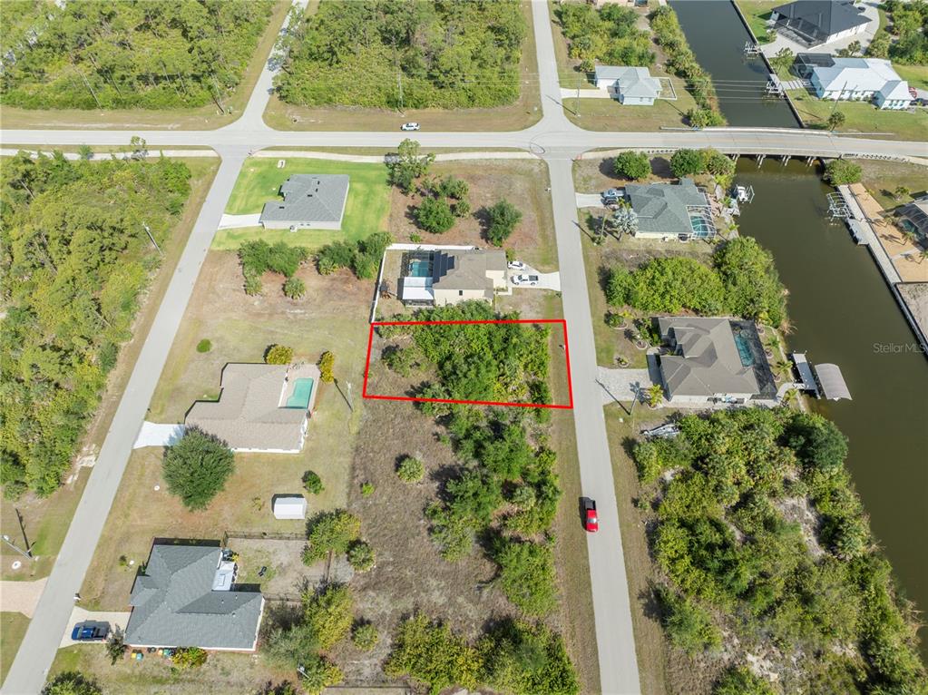 An aerial view shows a vacant, rectangular residential lot outlined in red between two houses — 14337 EDNA CIRCLE, PORT CHARLOTTE, FL