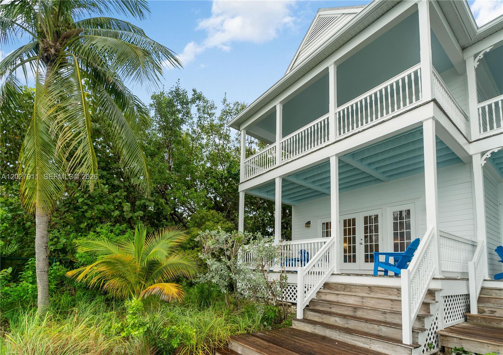 A two-story white house with blue porch ceilings and a wooden staircase sits outdoors — 2600 Overseas Hwy # 87, Marathon FL 33050, MARATHON, FL