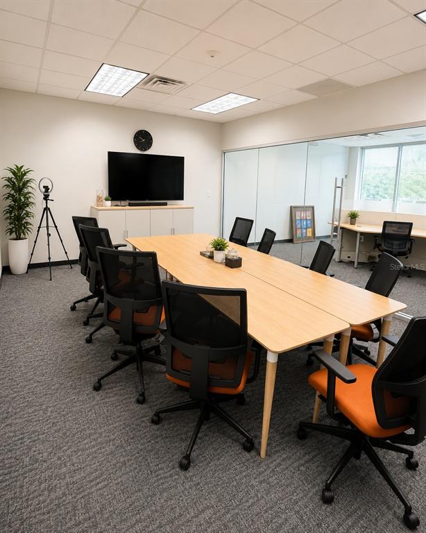 A conference room features a long wooden table, black office chairs, and a wall-mounted television — 3191 MAGUIRE BOULEVARD, ORLANDO, FL