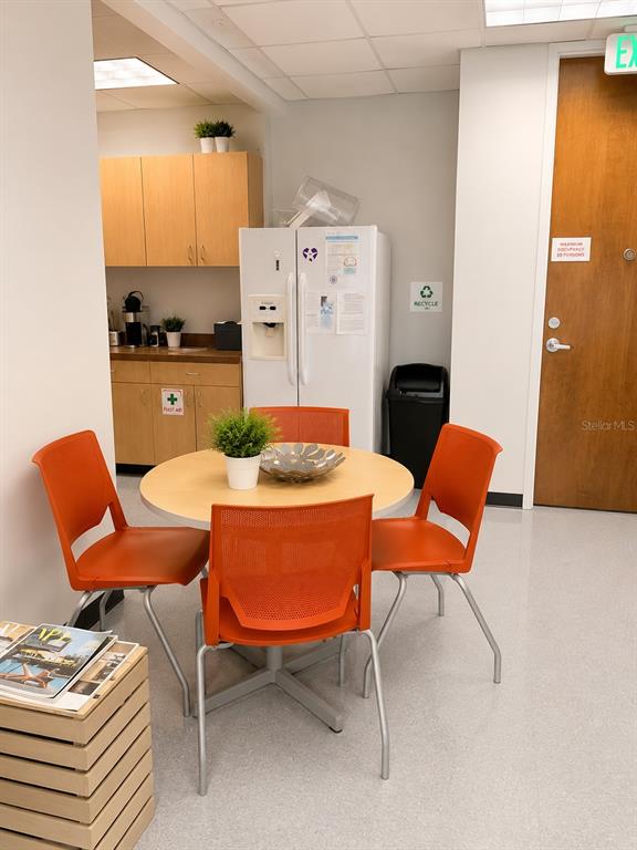 A breakroom features a round table with four orange chairs, a refrigerator, and wooden cabinetry — 3191 MAGUIRE BOULEVARD, ORLANDO, FL