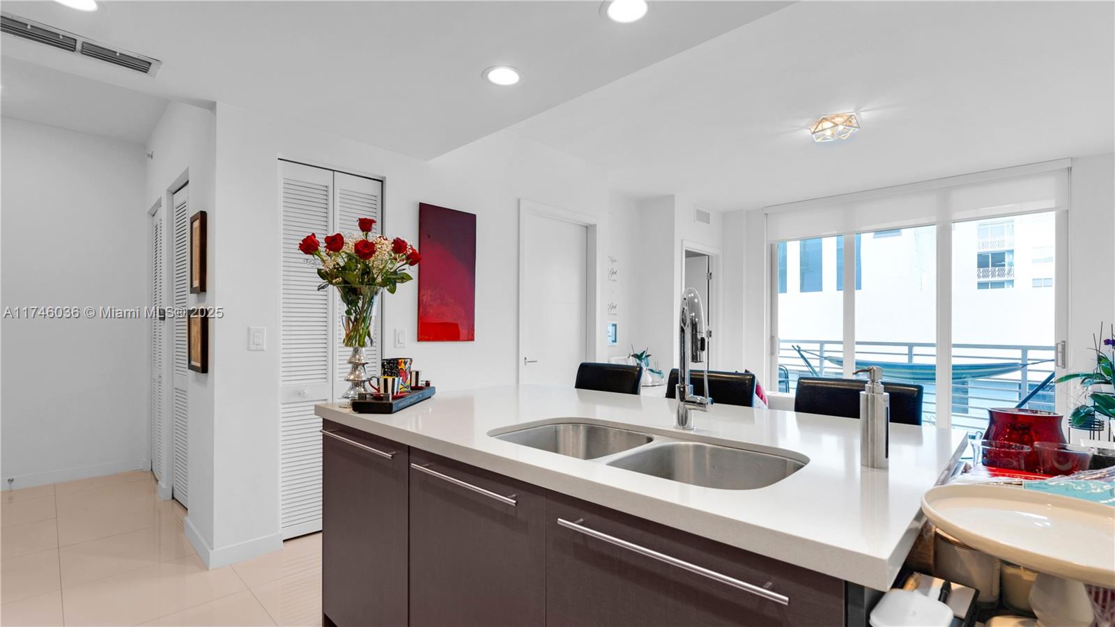 A modern kitchen features a central island with a double sink and dark cabinetry — 7875 NW 107th ave # 511, Doral FL 33178, DORAL, FL