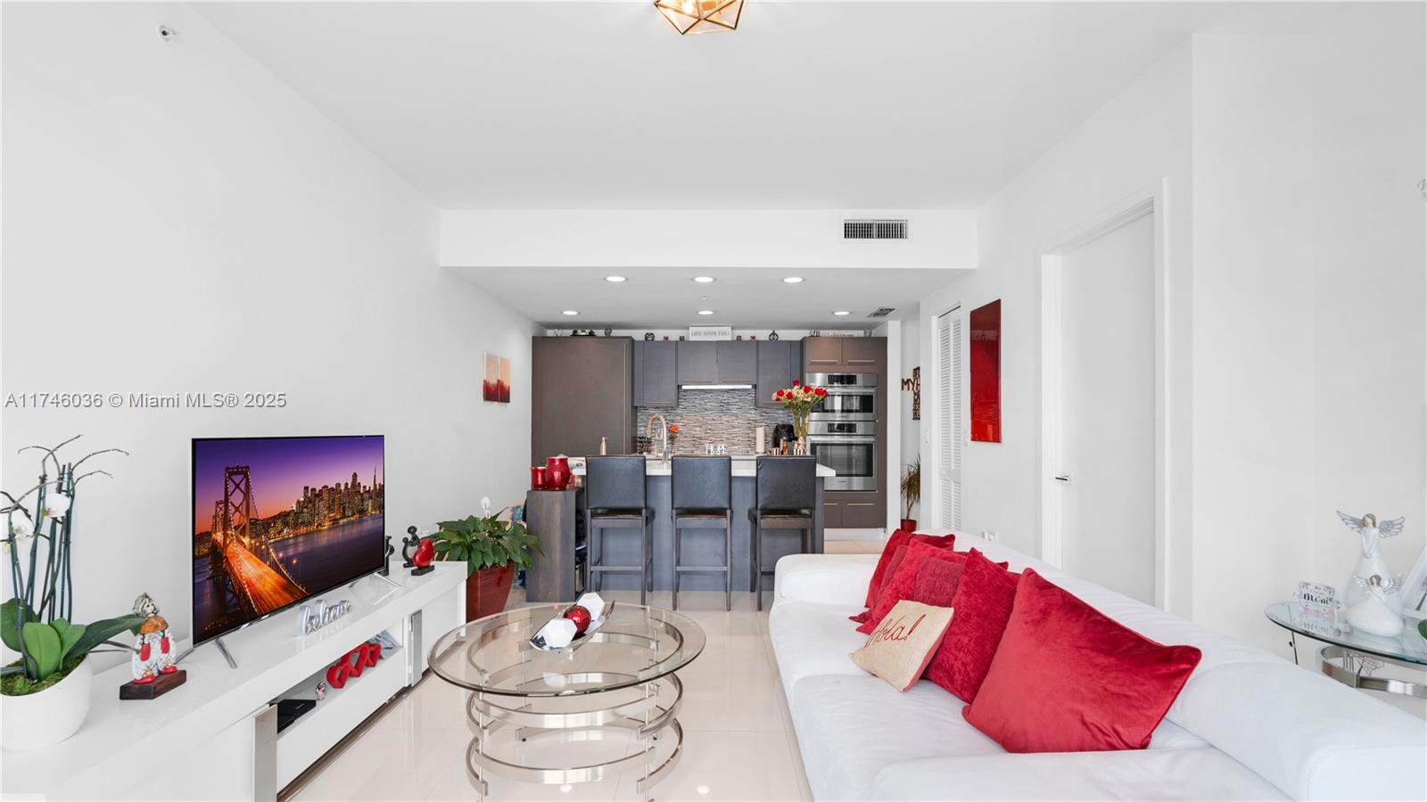 A modern living room features a white sofa, glass coffee table, and an open kitchen — 7875 NW 107th ave # 511, Doral FL 33178, DORAL, FL