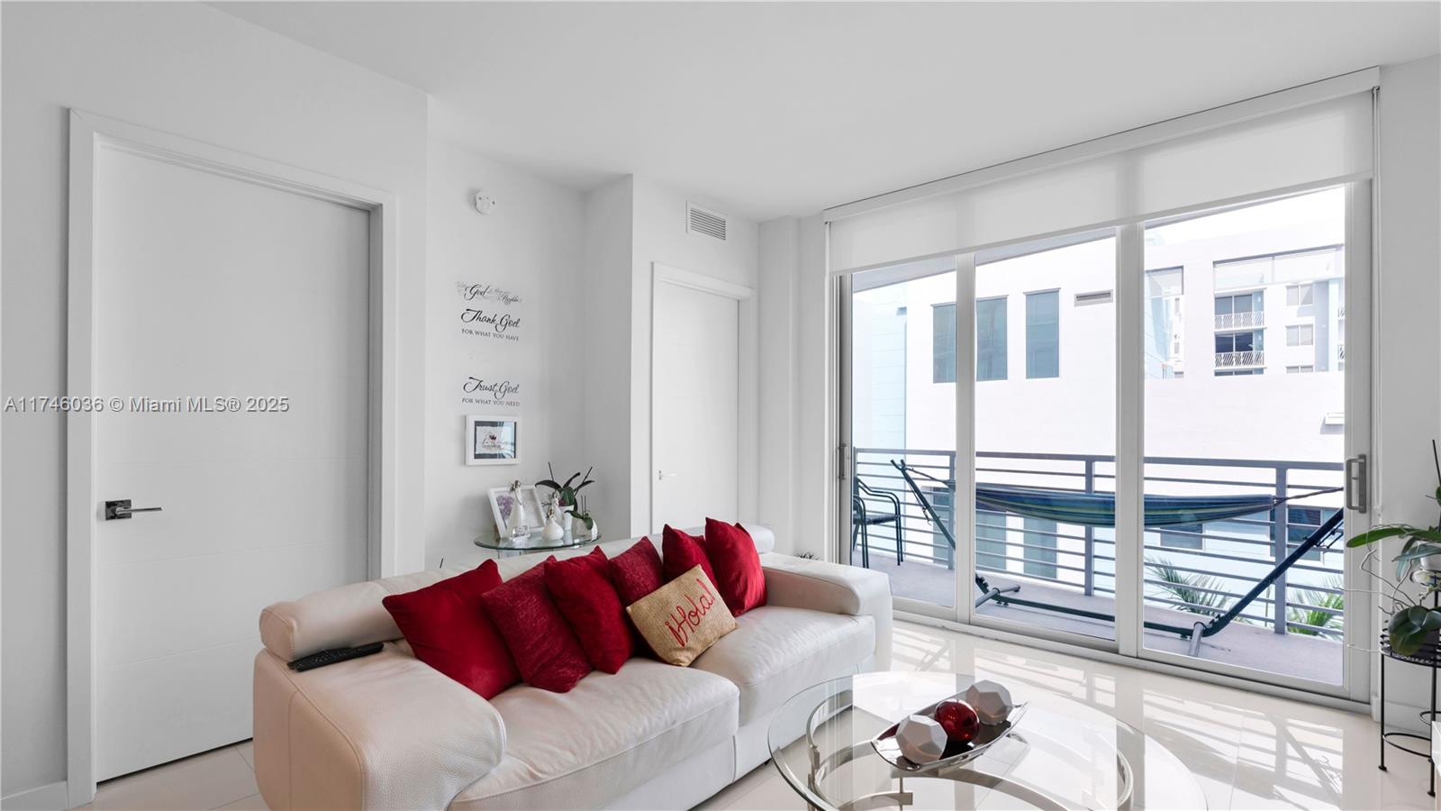 A living room features a white sofa with red pillows, a glass coffee table, and a balcony — 7875 NW 107th ave # 511, Doral FL 33178, DORAL, FL