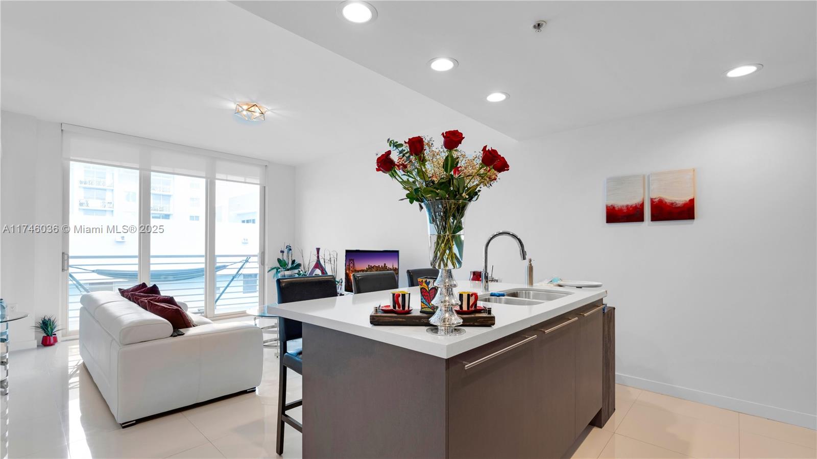 A modern kitchen island with a vase of roses sits before a living area — 7875 NW 107th ave # 511, Doral FL 33178, DORAL, FL
