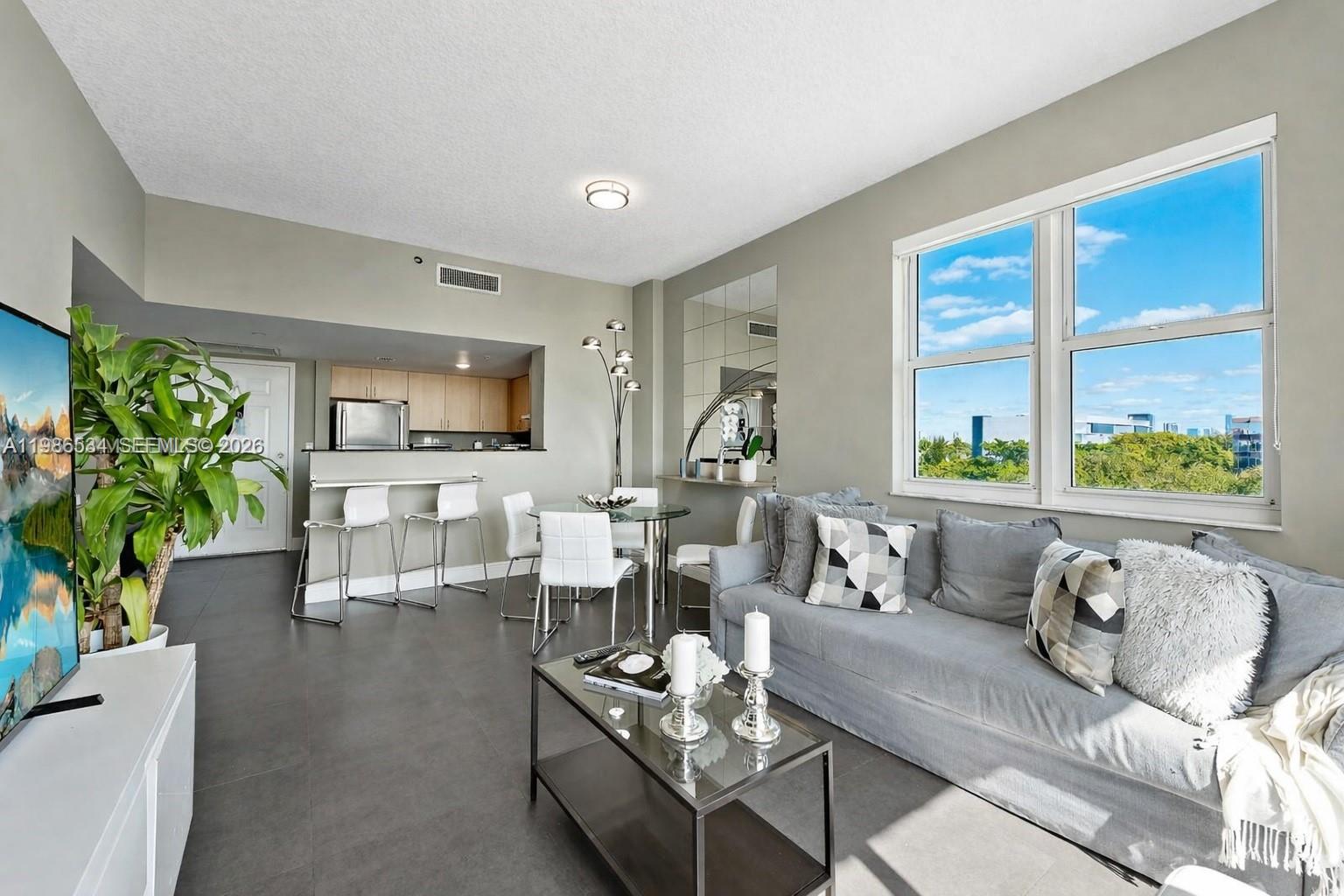 A living room with gray tile floors, a sofa, a dining area, and an open kitchen — 3000 CORAL WAY # 416, Miami FL 33145, MIAMI, FL