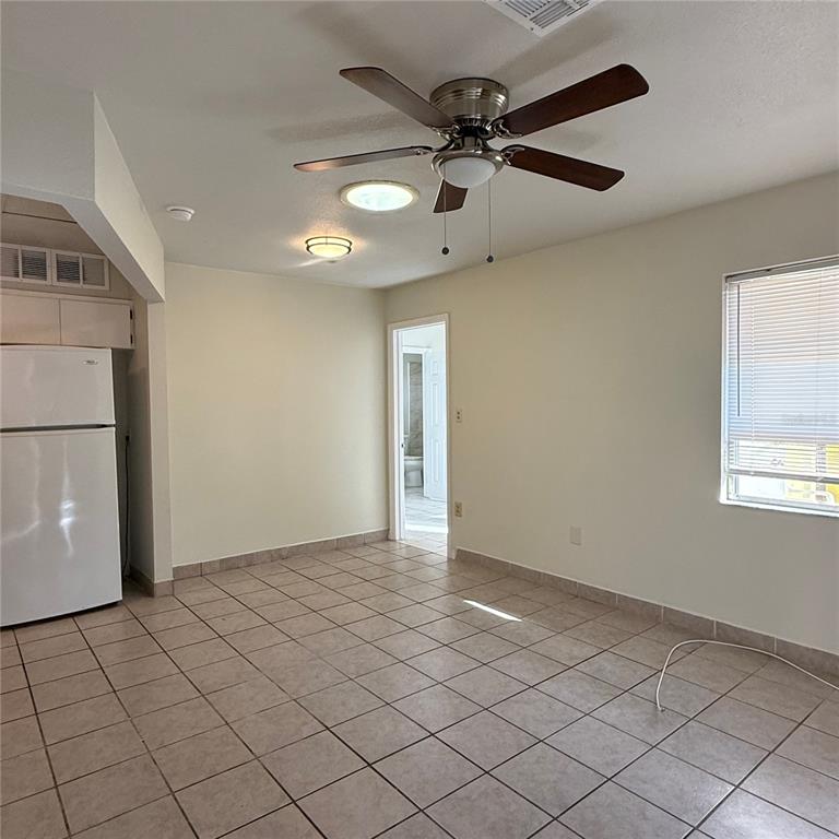 A room with tile flooring, a ceiling fan, a white refrigerator, and a doorway — 328 ORTIZ BOULEVARD UNIT B, NORTH PORT, FL