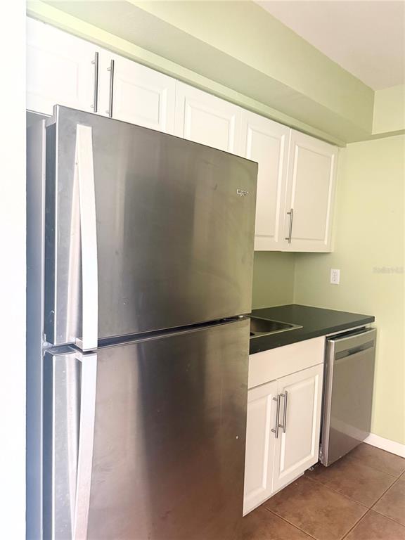 A kitchen features white cabinets, stainless steel appliances, and a black countertop — 1000 LAKE OF THE WOODS BOULEVARD UNIT 101B, CASSELBERRY, FL