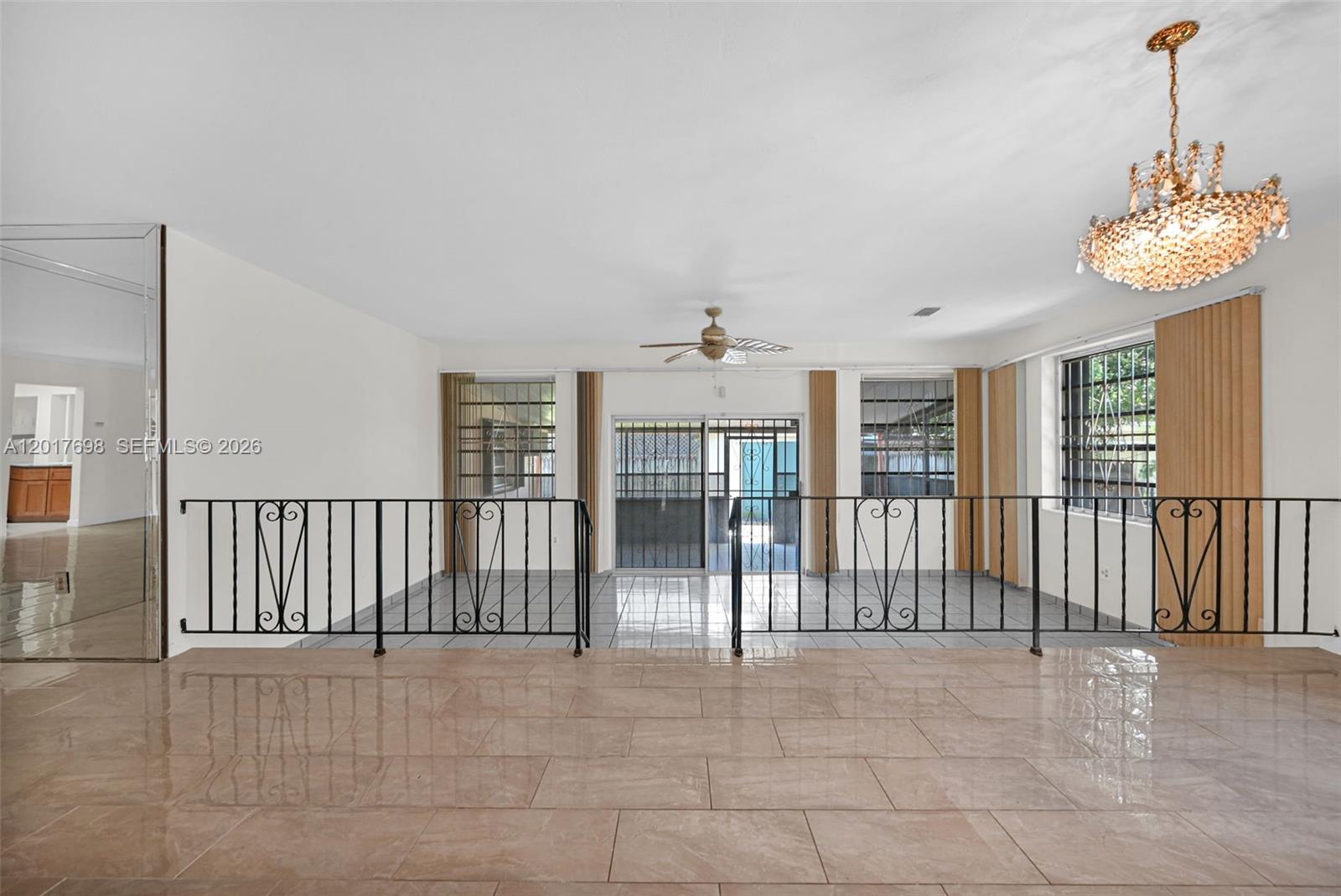 A split-level living area features tiled floors, a wrought iron railing, and a crystal chandelier — 244 NW 43rd St # 0, Miami FL 33127, MIAMI, FL