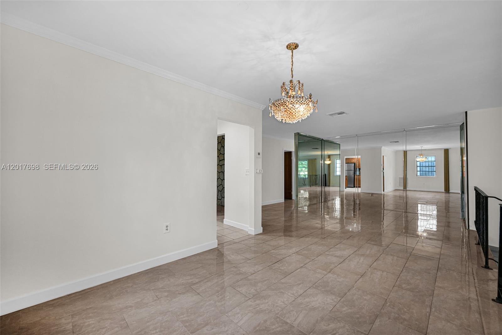 A spacious room features light-colored tile flooring, a crystal chandelier, and mirrored wall panels — 244 NW 43rd St # 0, Miami FL 33127, MIAMI, FL
