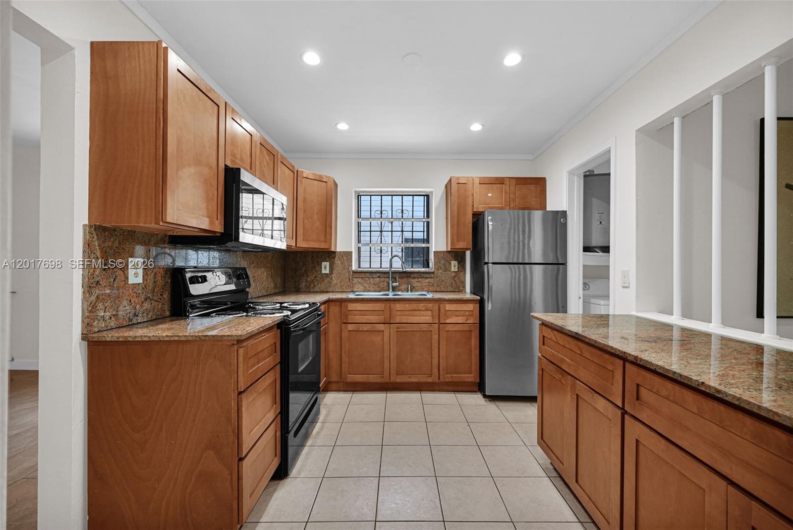 A kitchen features wood cabinets, granite countertops, stainless steel appliances, and beige tile flooring — 244 NW 43rd St # 0, Miami FL 33127, MIAMI, FL