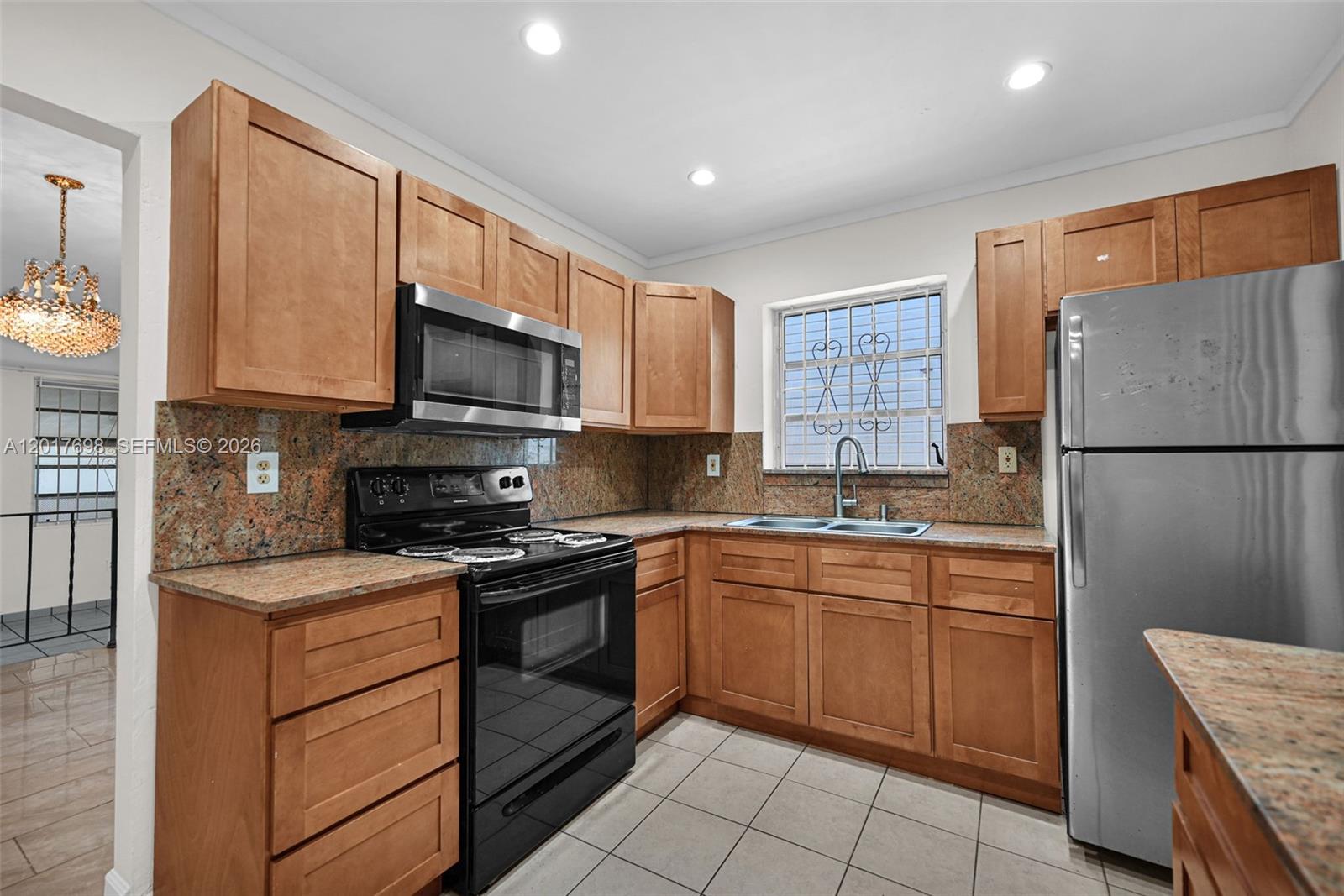 A kitchen features wood cabinets, granite countertops, stainless steel appliances, and a window with security bars — 244 NW 43rd St # 0, Miami FL 33127, MIAMI, FL