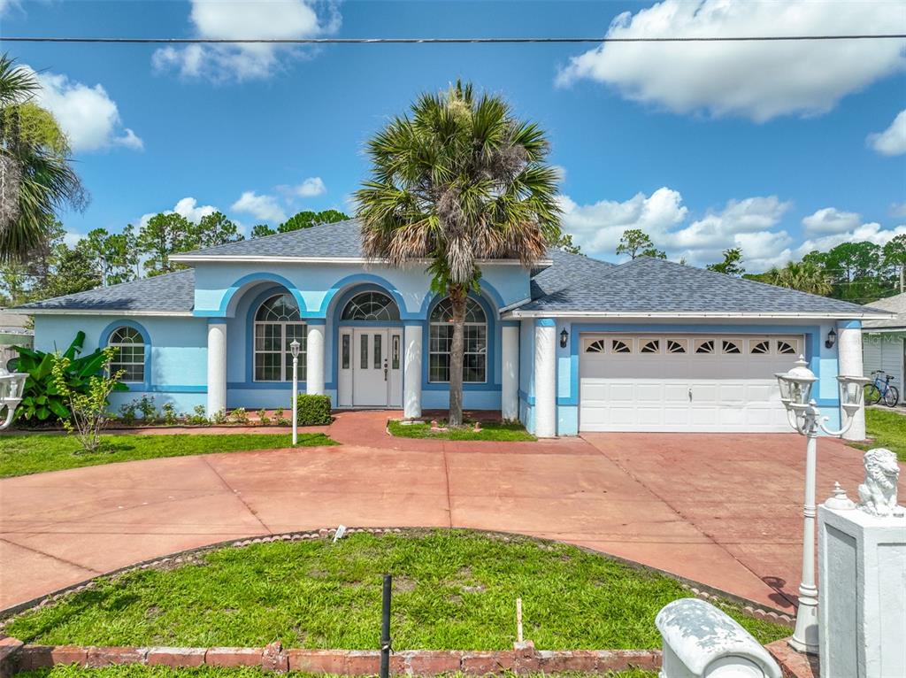 A light blue single-story house with a white garage and a curved driveway — 4 RAINSTONE LANE, PALM COAST, FL