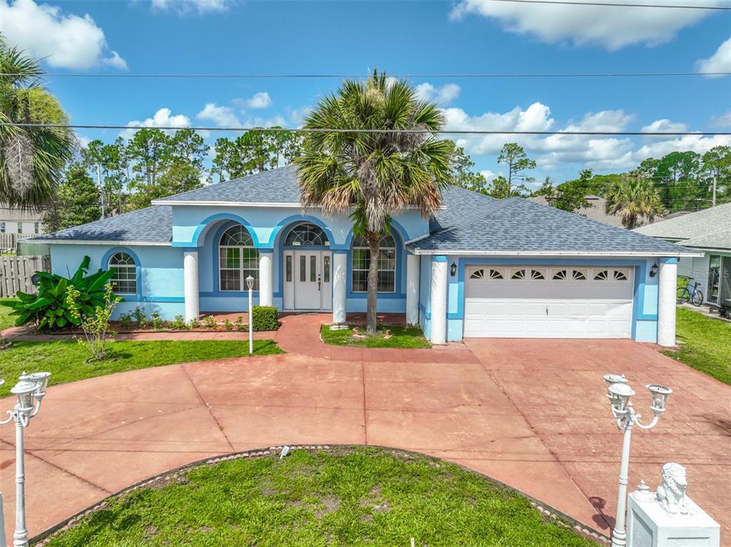 A light blue single-story house with a white garage door and a palm tree — 4 RAINSTONE LANE, PALM COAST, FL