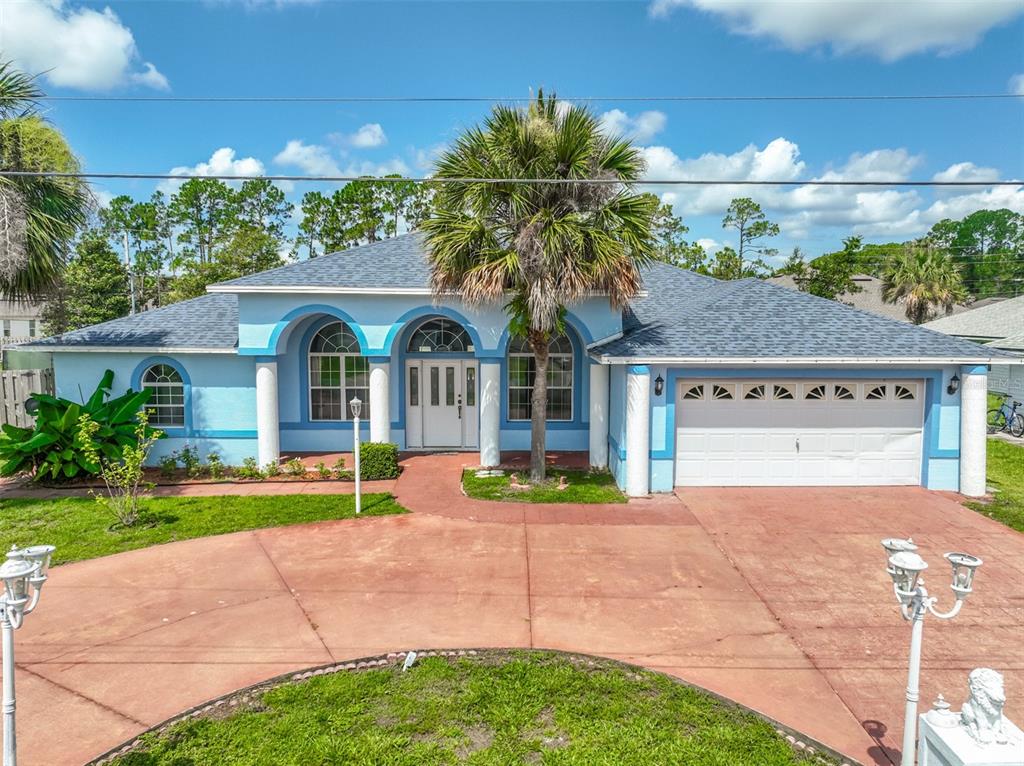 A light blue single-story house with a white garage, arched windows, and a palm tree — 4 RAINSTONE LANE, PALM COAST, FL
