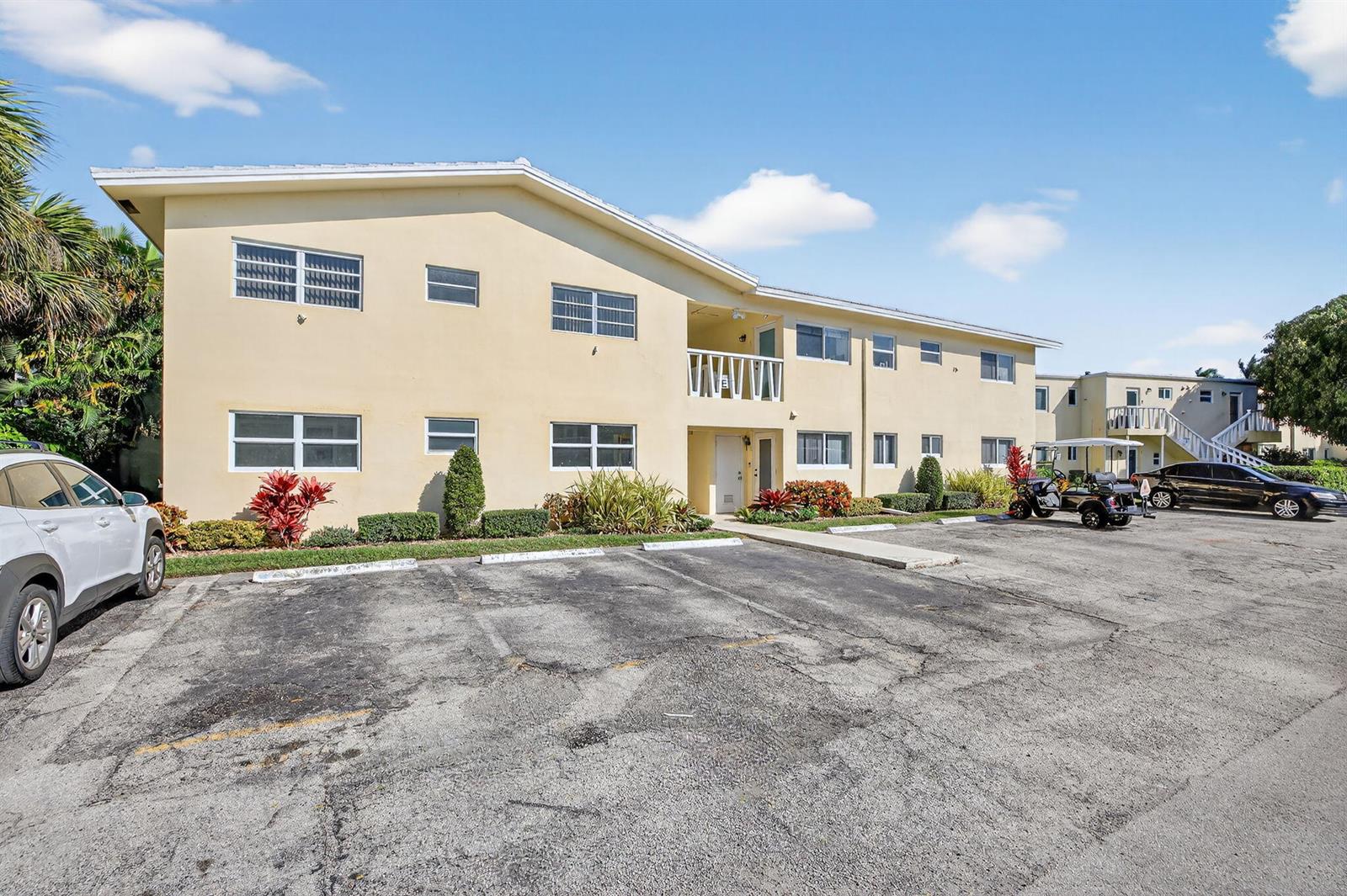 A two-story apartment building with a parking lot in front under a blue sky — 2755 NE 28th Avenue # E2, Lighthouse Point FL 33064, LIGHTHOUSE POINT, FL