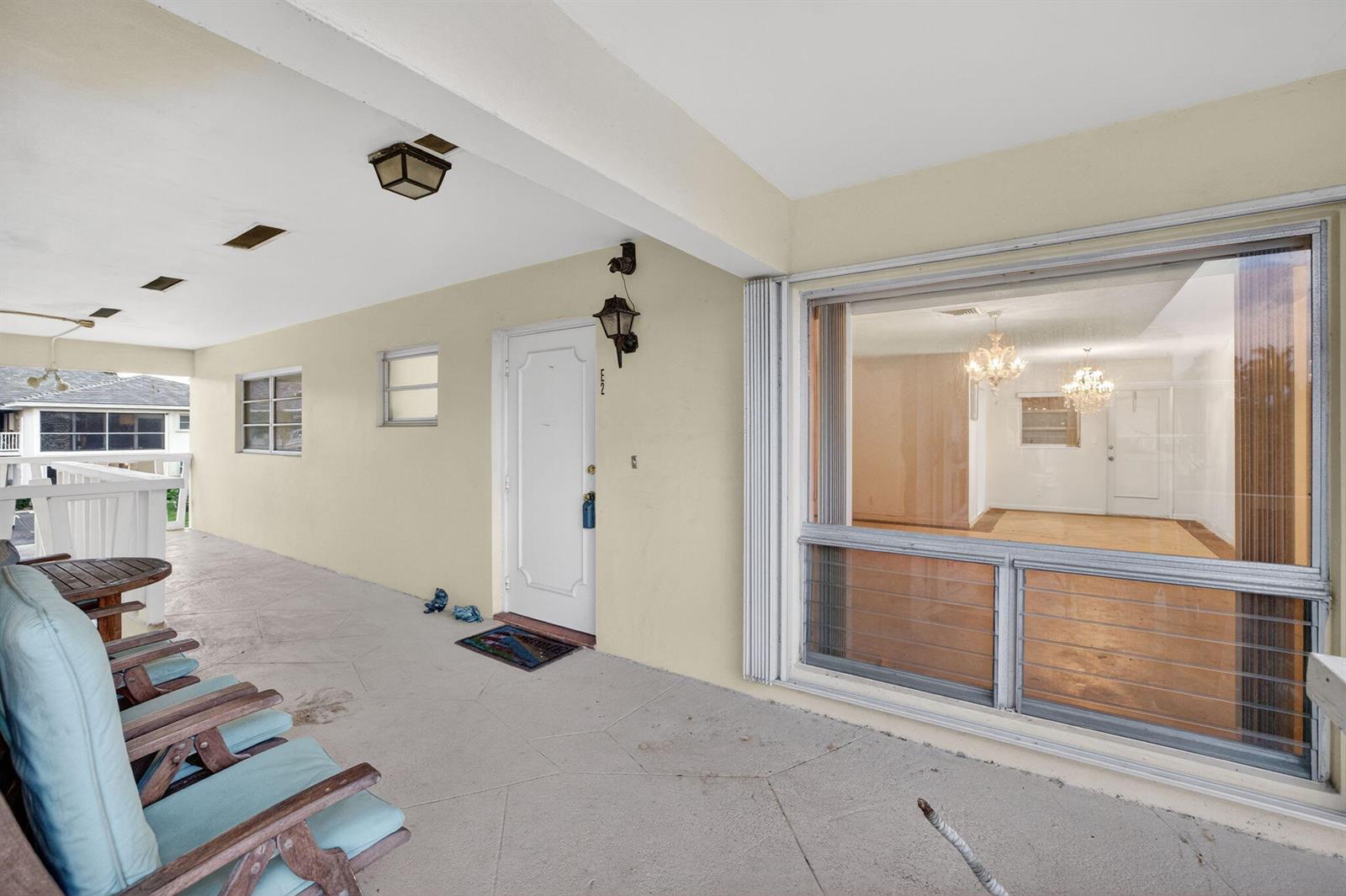 A covered patio features a white door, a large window, and outdoor seating — 2755 NE 28th Avenue # E2, Lighthouse Point FL 33064, LIGHTHOUSE POINT, FL