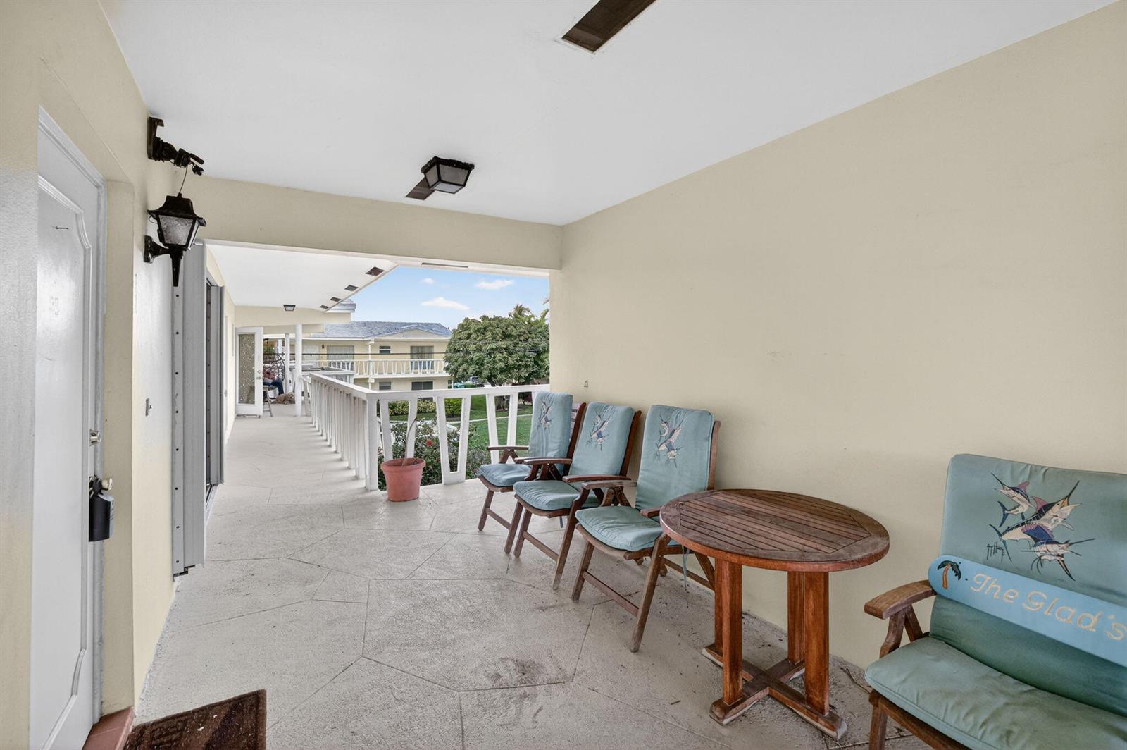 A covered outdoor balcony features a concrete floor, wooden furniture, and a white railing — 2755 NE 28th Avenue # E2, Lighthouse Point FL 33064, LIGHTHOUSE POINT, FL