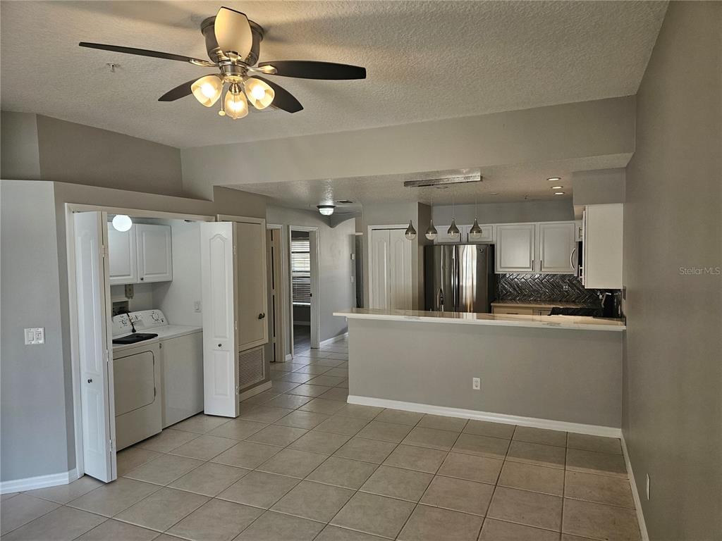 A kitchen with white cabinets and a breakfast bar overlooks a tiled dining area — 673 SANDY NECK LANE UNIT 103, ALTAMONTE SPRINGS, FL