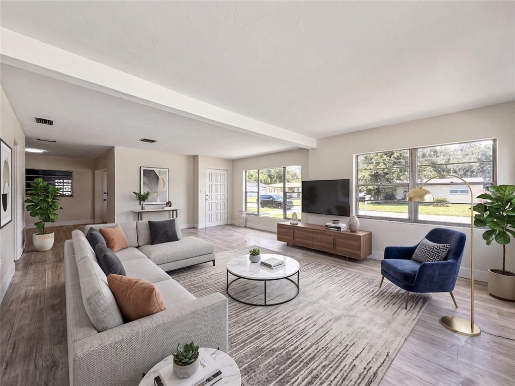 A spacious, empty living room features light wood-look flooring, white walls, and several windows — 3502 ARCH STREET, ORLANDO, FL