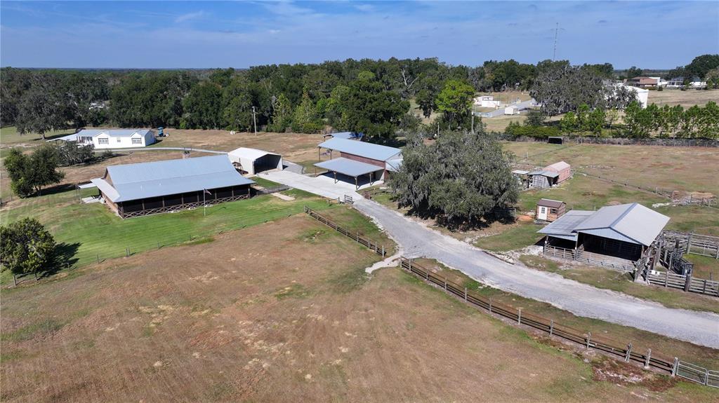 An aerial view shows a rural property with multiple barns, outbuildings, and fenced pastures — 3182 INDIAN RIDGE PLACE, LAKELAND, FL